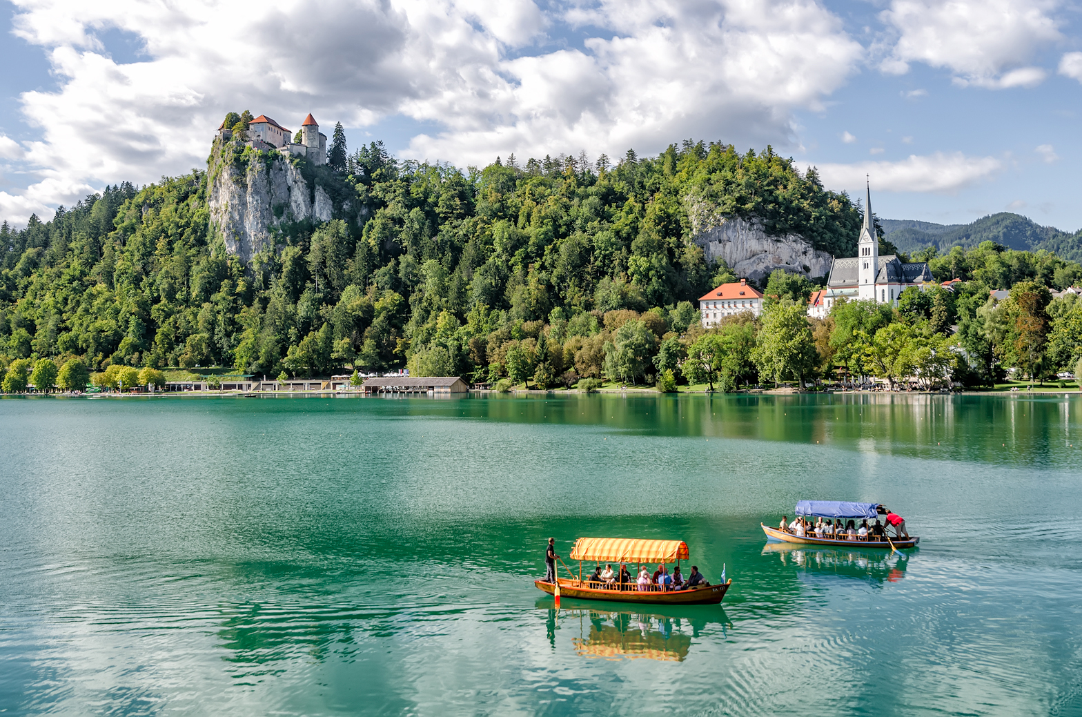 Lake Bled with Pletnas rowing across and Bled Castle keeping watch above