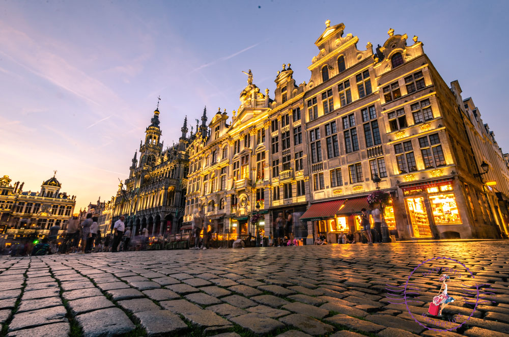 A picture of the Grand Place Brussels all lit up at night, showing the world's first Godiva store